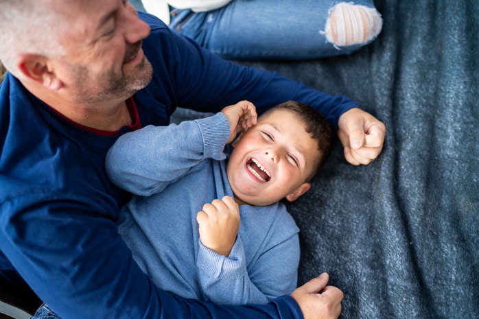 A family of three enjoys a happy moment sitting together on a park blanket.