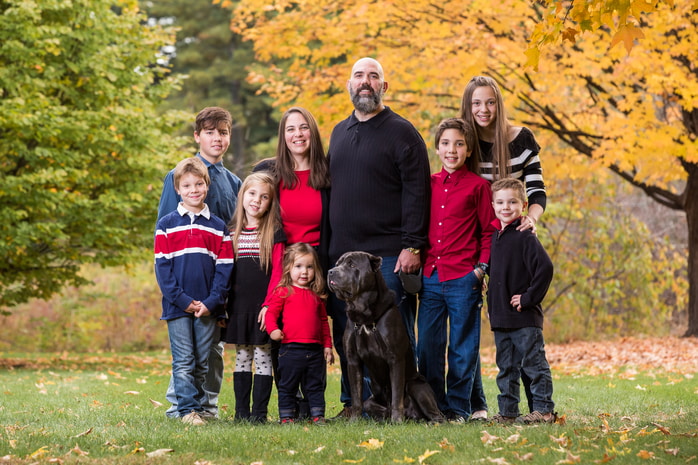 Large extended family posing together for a group photo in a beautiful park setting.