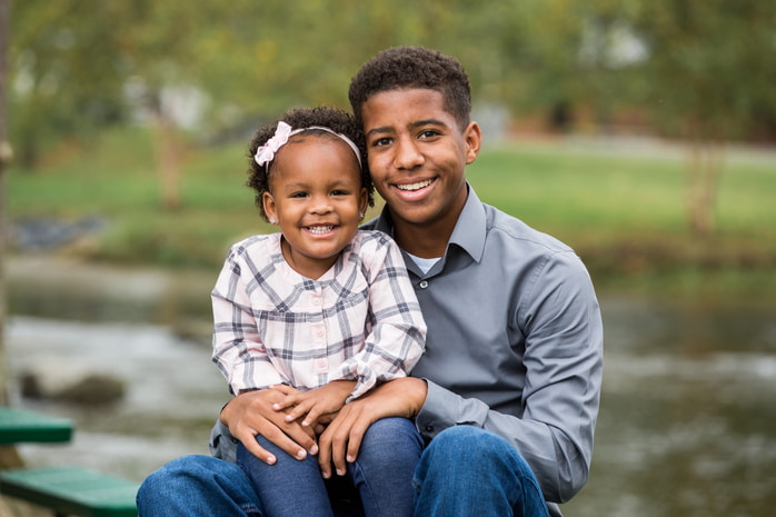A mother and father swinging their young daughter between them as they walk through a field.